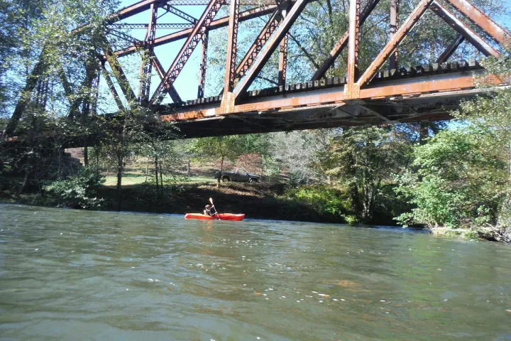 a man kayaking under the bridge